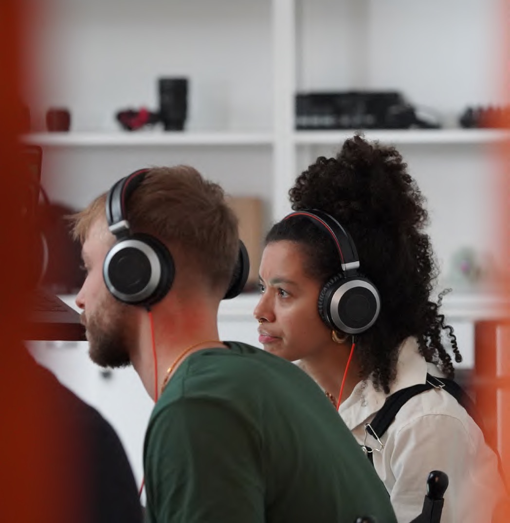 Two colleagues in headphones watching a webinar together
