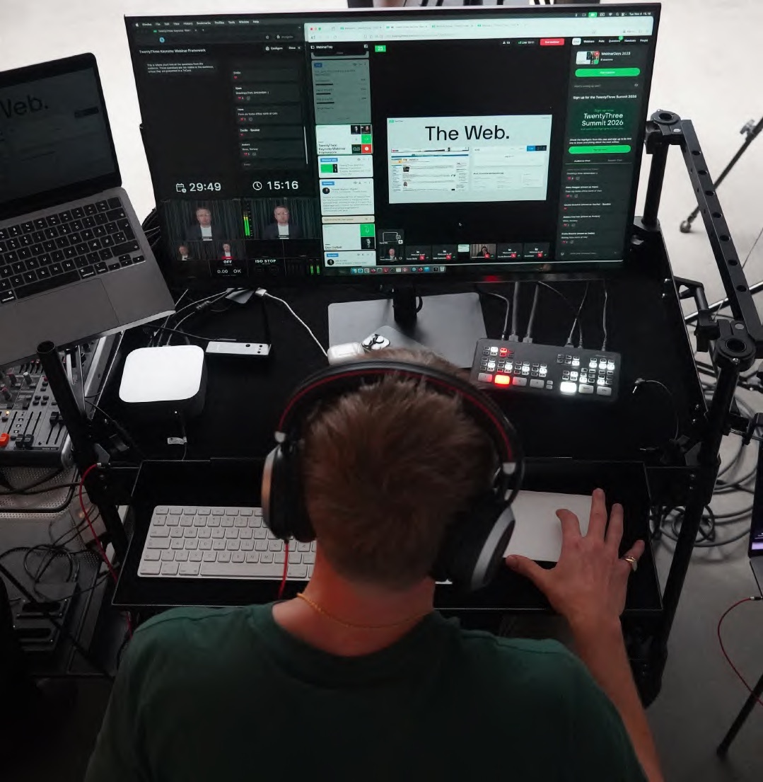 A producer operating a webinar production desk with mixer and monitors